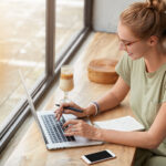 A girl uses a laptop by the window